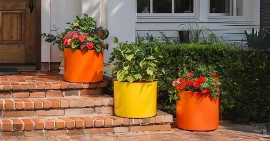 yellow and orange plant grow bags with flowers in them on a front porch