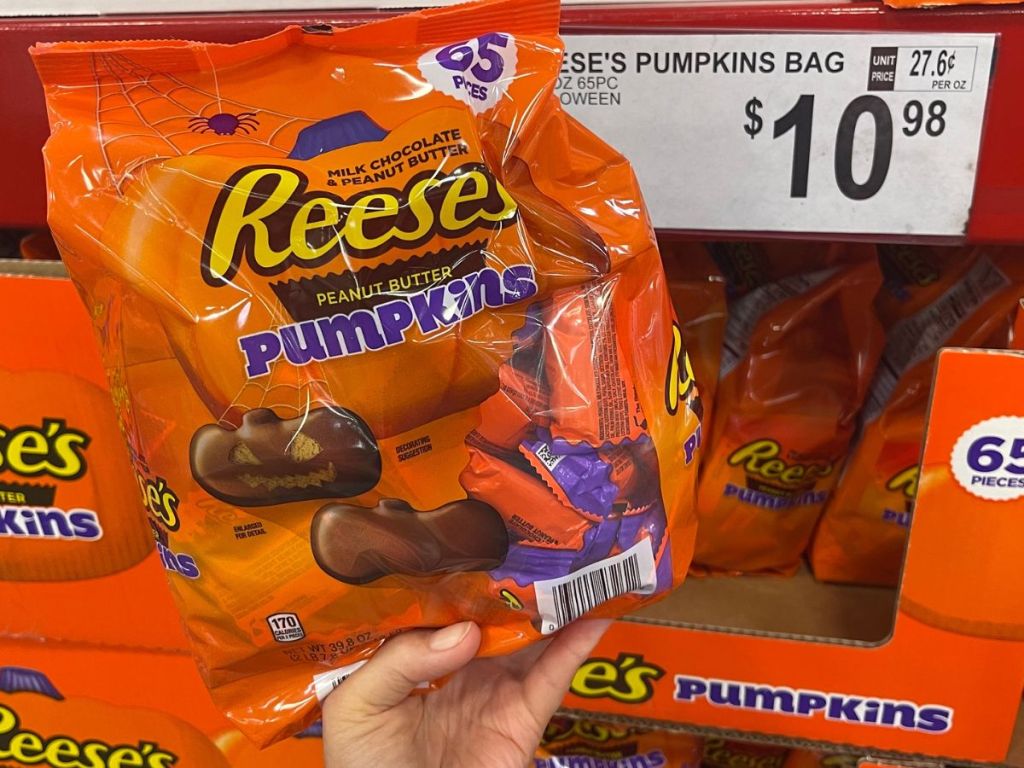 Hand holding up a bag of Reese's peanut butter pumpkins