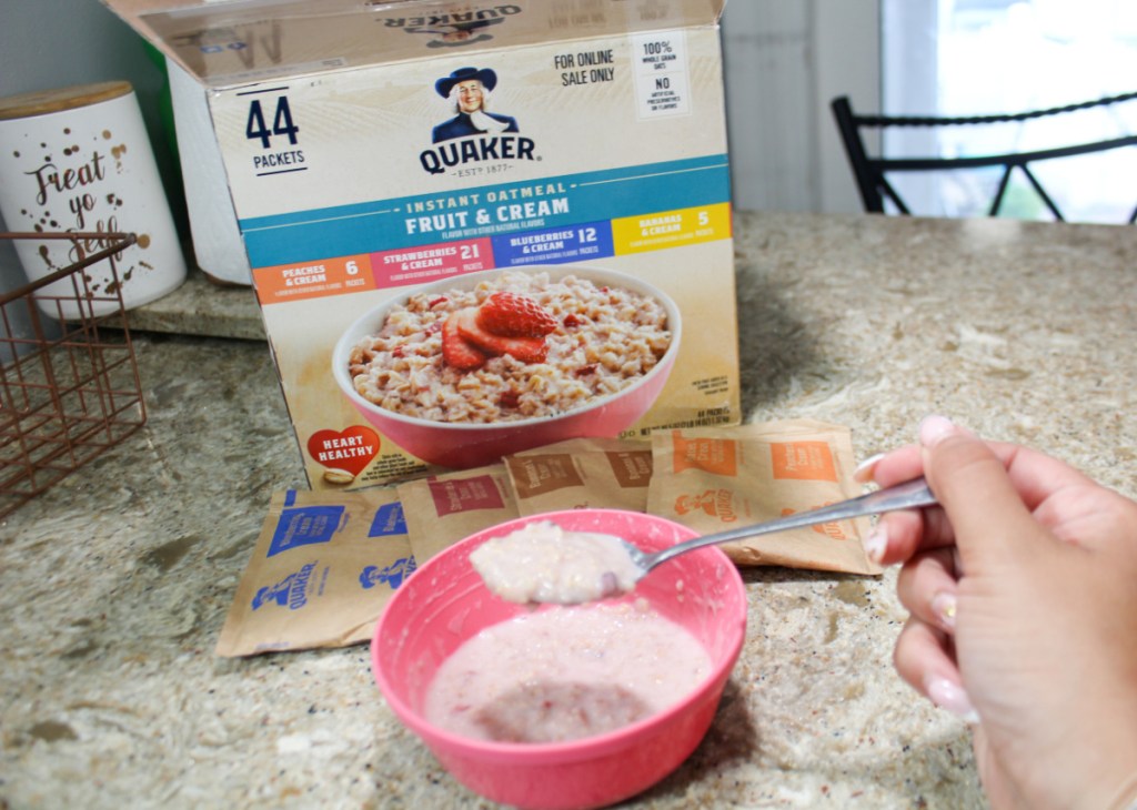 hand holding a spoonful of quaker oatmeal fruit and cream variety