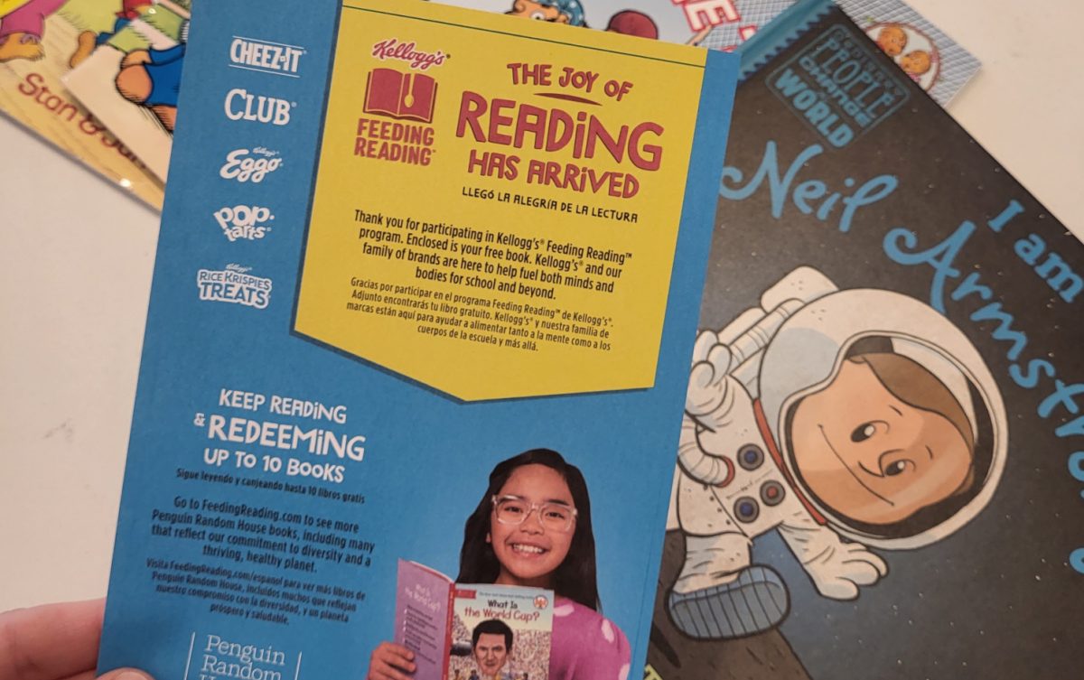 Hand holding up a book with a promo for The Kelloggs Feeding Reading Program