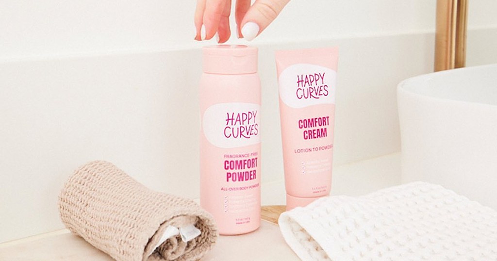 hand grabbing a pink bottle of Happy Curves Comfort Powder