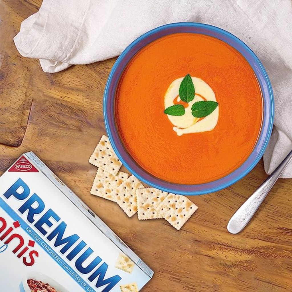 Premium Mini Saltine Crackers box and crackers shown with bowl of soup