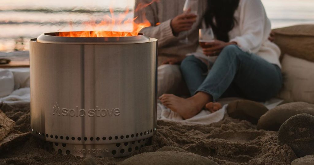 couple sitting on the beach by a Solo Stove Bonfire 2.0 w/ Stand, Starter Packs and Pellet Adapter