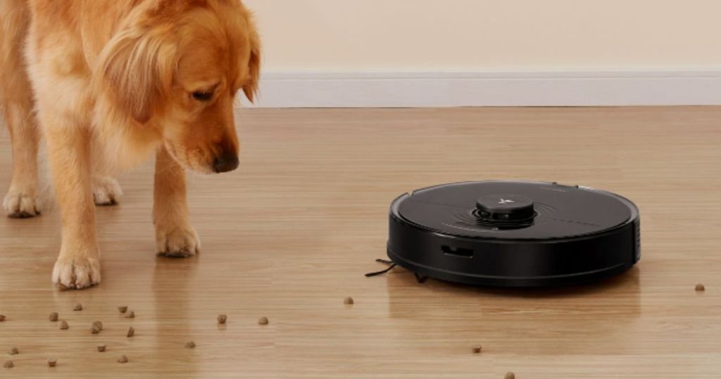 Roborock S7 Robot Vacuum with Sonic Mop shown vacuuming up spilled dog food and dog looking at it
