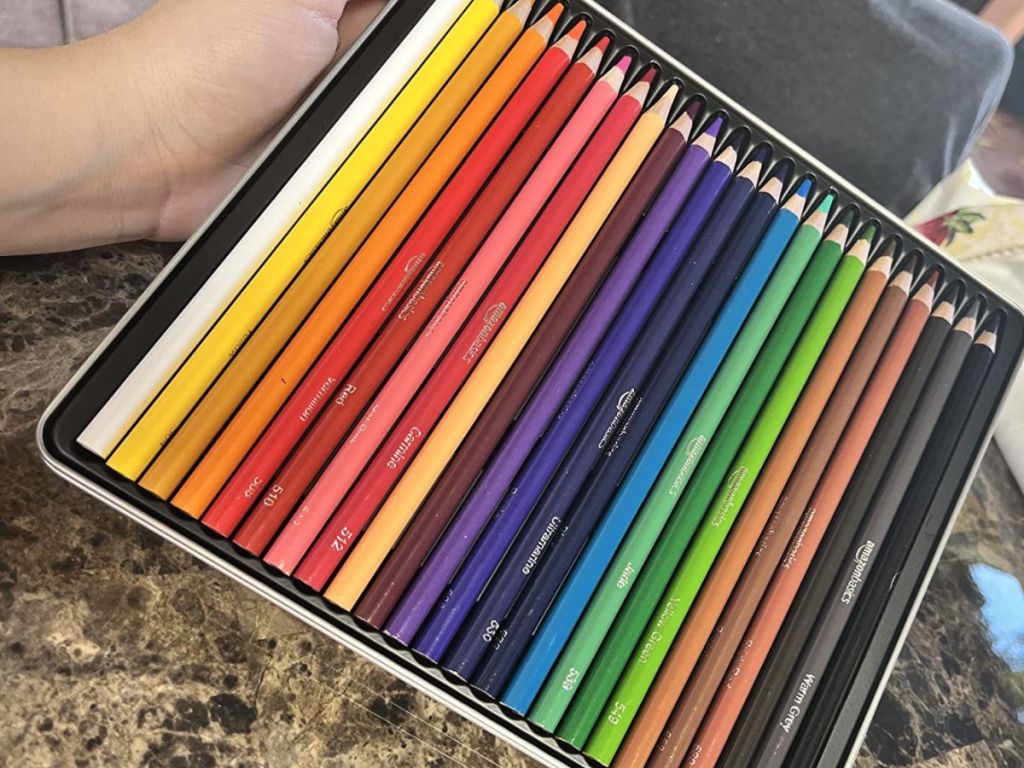 Amazon Basics Premium Colored Pencils, Soft Core, 24 Count shown in woman's hand on a countertop
