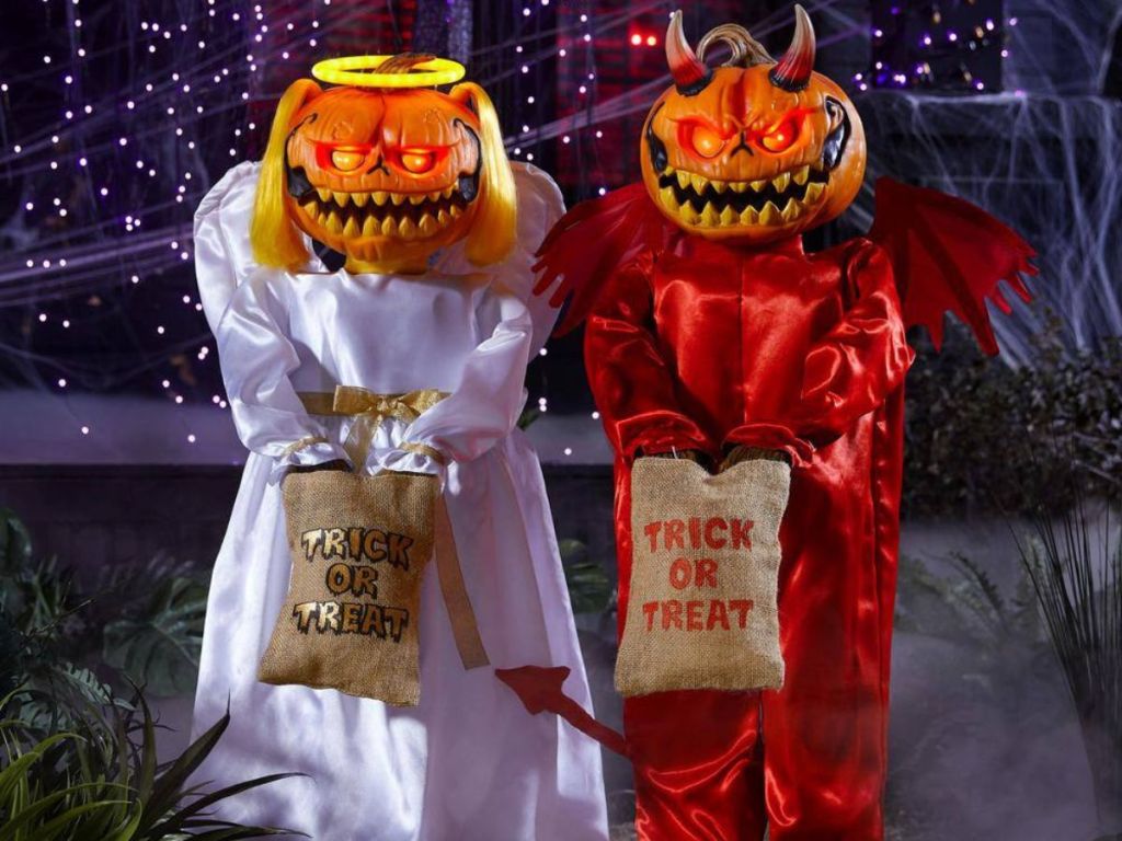 two animatronic pumpkin head twins dressed as a devil and an angel