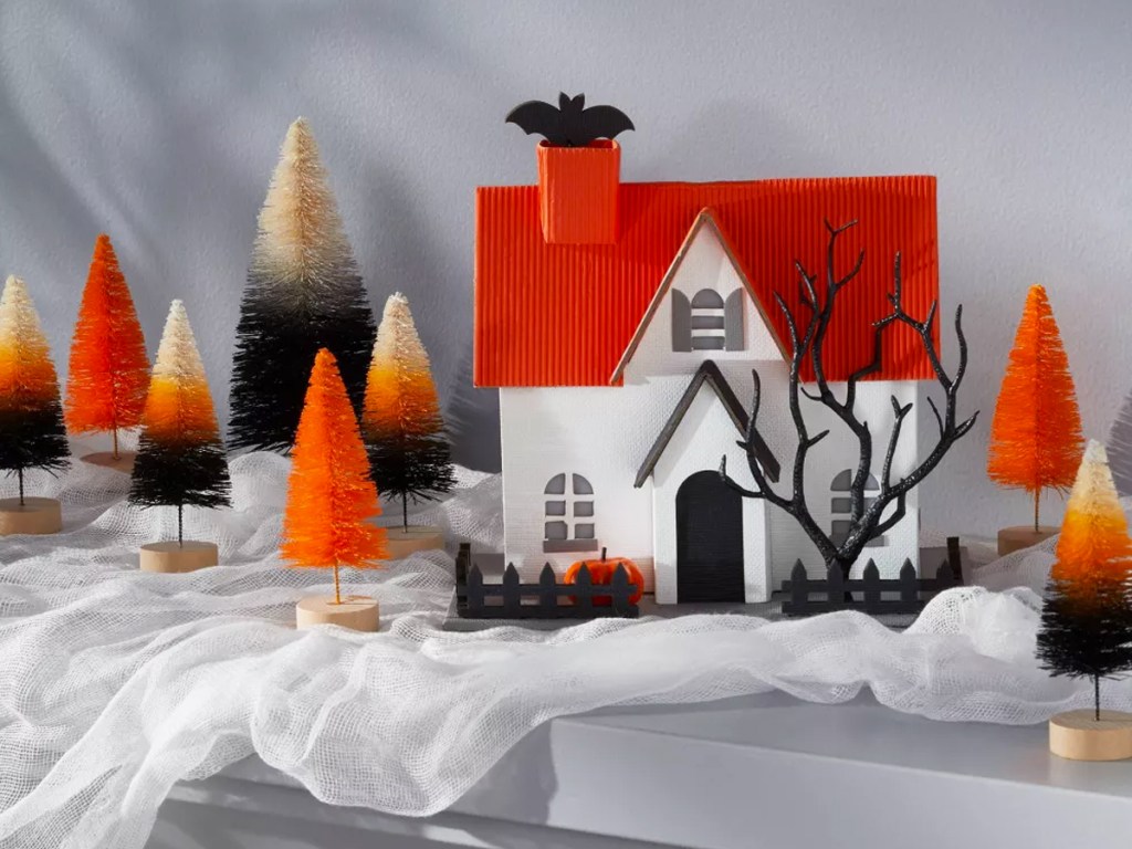 halloween house surrounded by orange and black bottle brush trees