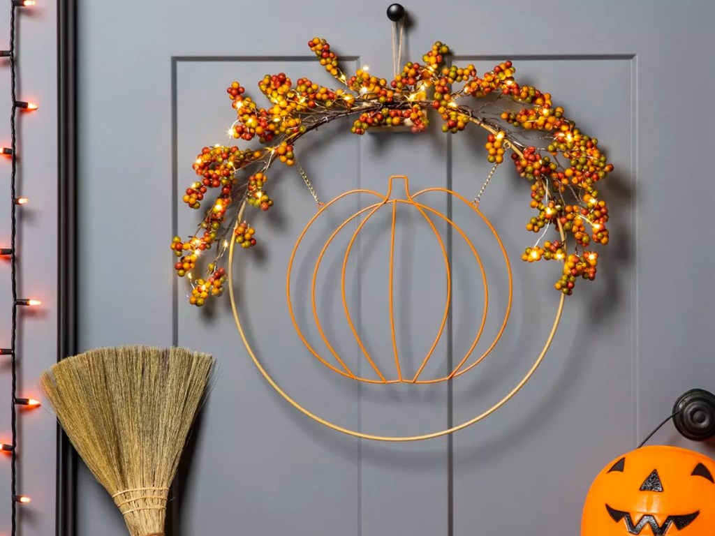 wire pumpkin wreath with lights on a door