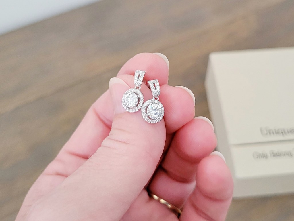 hand holding a pair of moissanite earrings