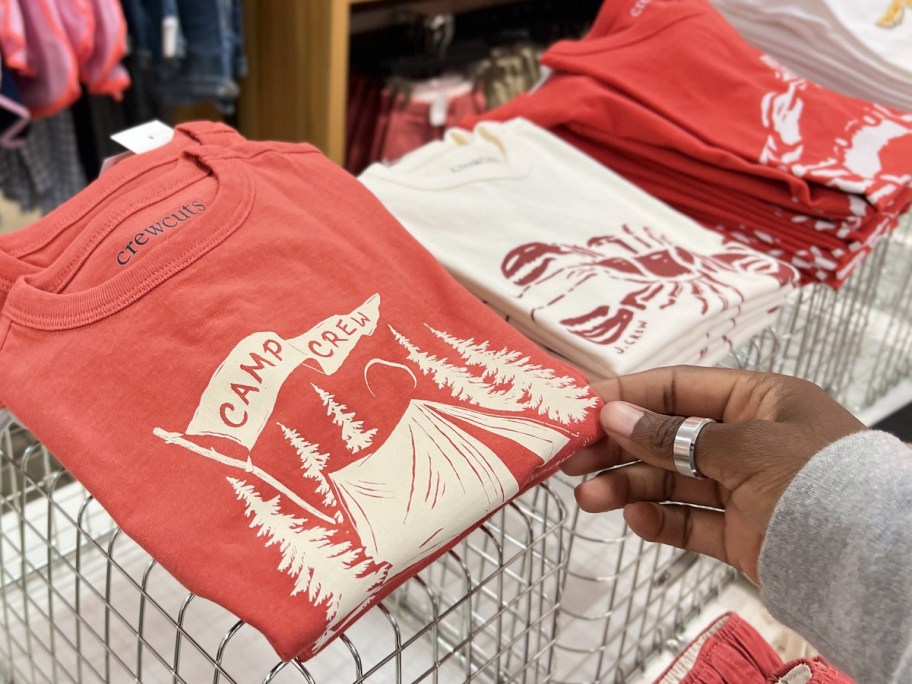 hand touching red graphic tee on display in store