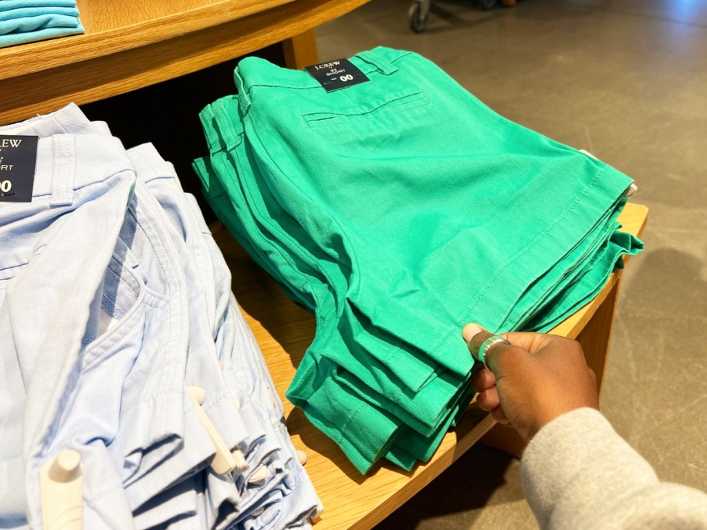 hand touching a pair of green women's shorts