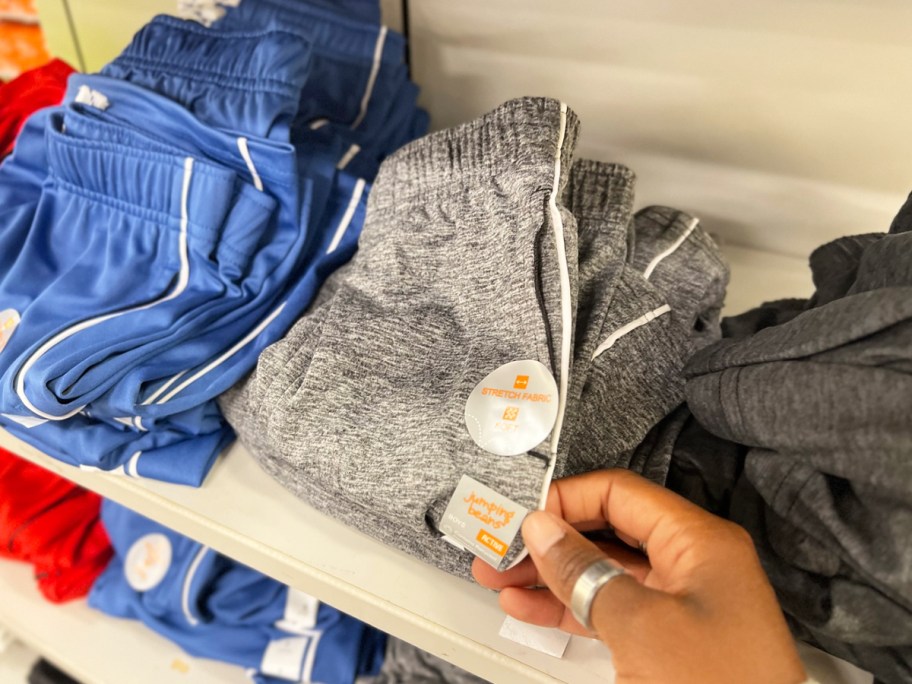hand touching pair of grey shorts on store shelf