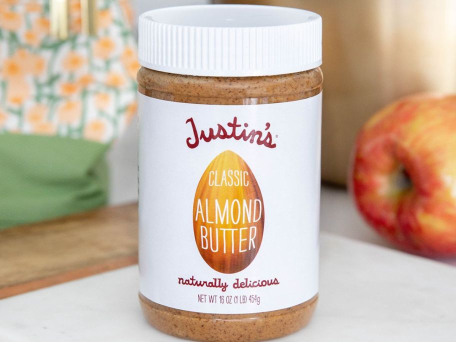 Justin's Classic Almond Butter on a counter next to an apple