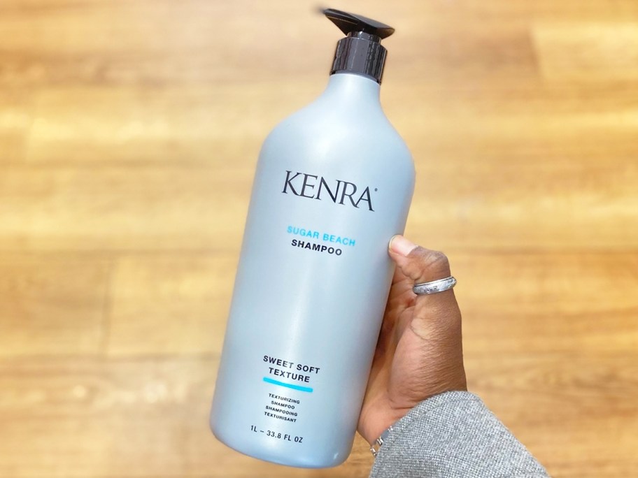 hand holding liter bottle of kenra shampoo