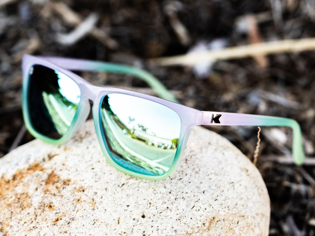 purple and green sunglasses on a rock