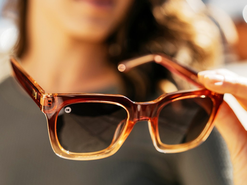 woman holding a brown pair of sunglasses