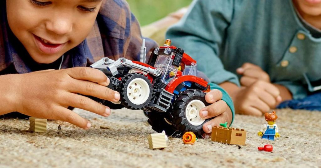 2 kids playing with a lego tractor