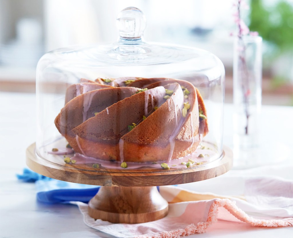 brown cake on a wood stand with glass dome