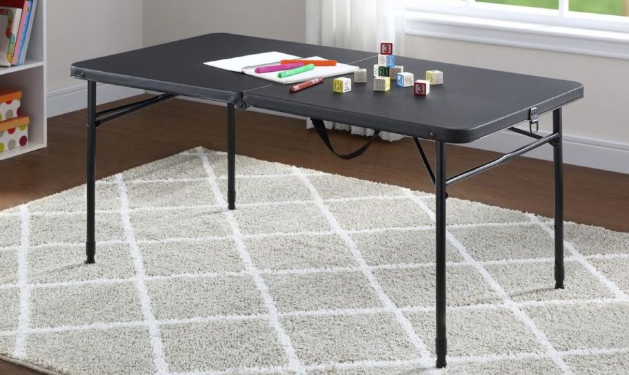 a 4 foot plastic bifold table set up in a room on a gray rug