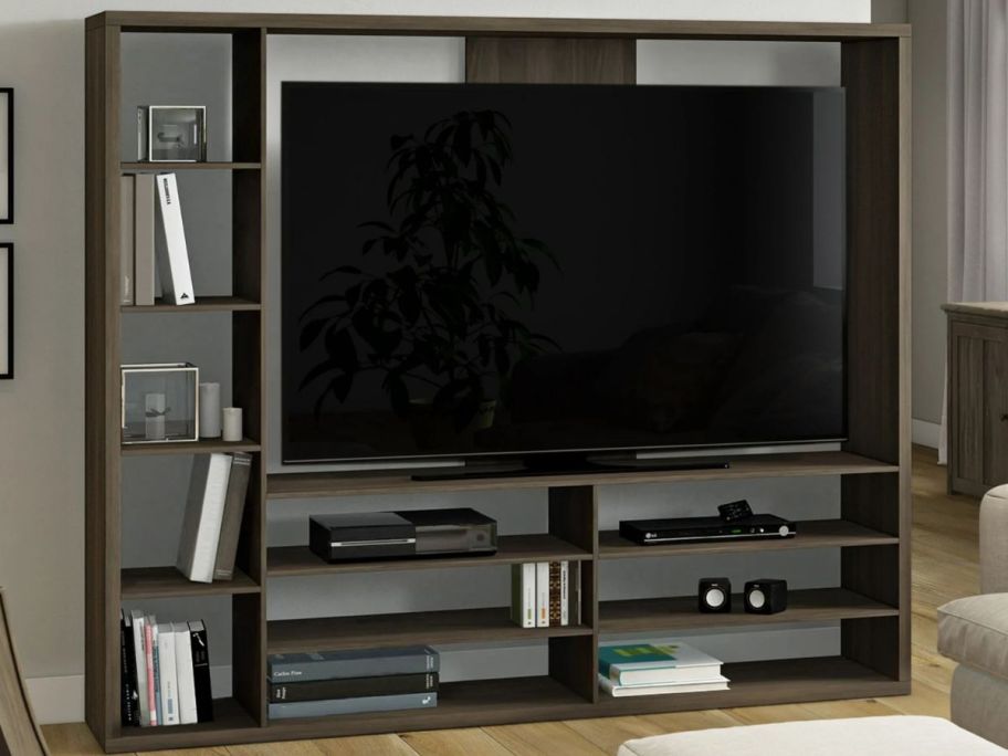 A large mainstays TV stand from walmart with a TV and other media on it