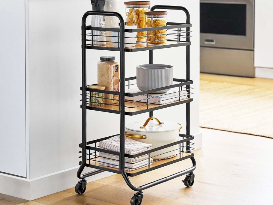 black rolling cart filled with kitchen items on each shelf