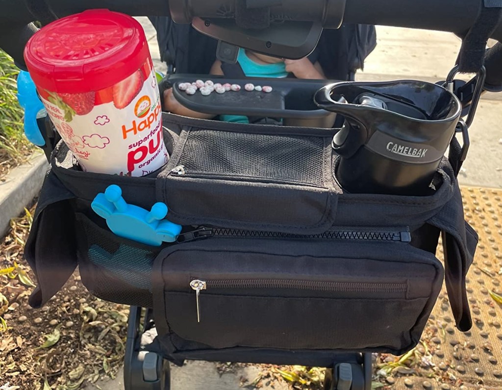 Stroller organizer with a canister of puffs and a coffee mug in it
