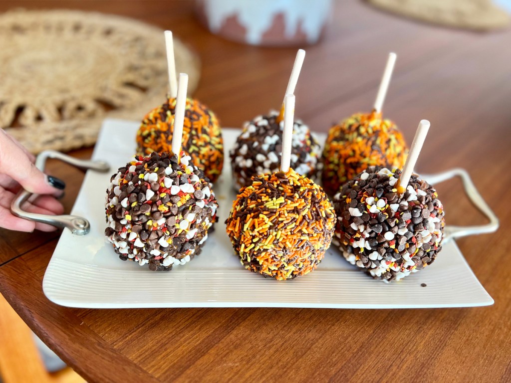 sprinkled covered caramel apples on a white tray