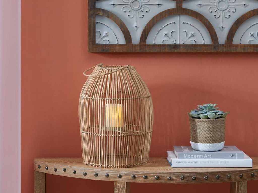 Natural Rattan Lantern with light inside displayed next to books and a plant