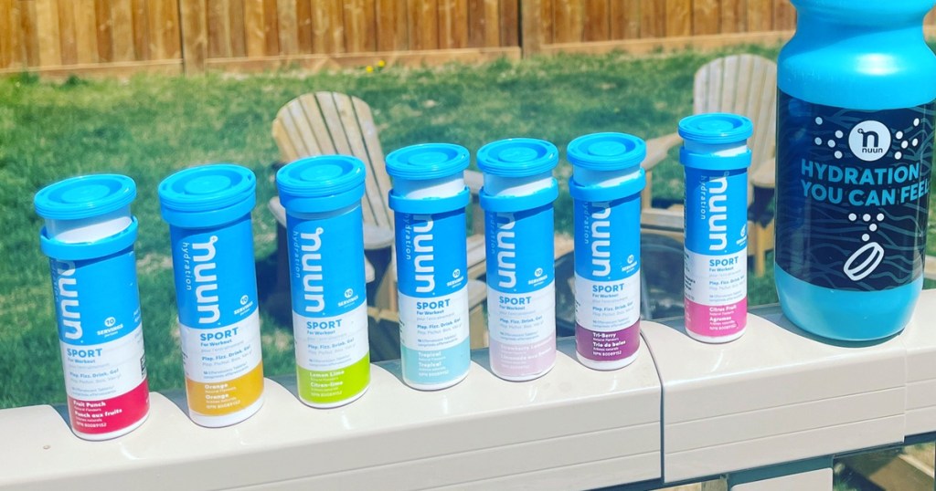 multiple tubes of nuun hydration tablets in a row on a deck railing with a water bottle
