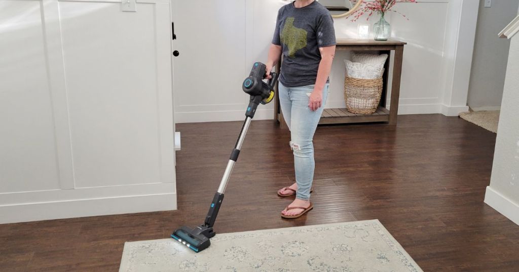 woman using stick vacuum on carpet