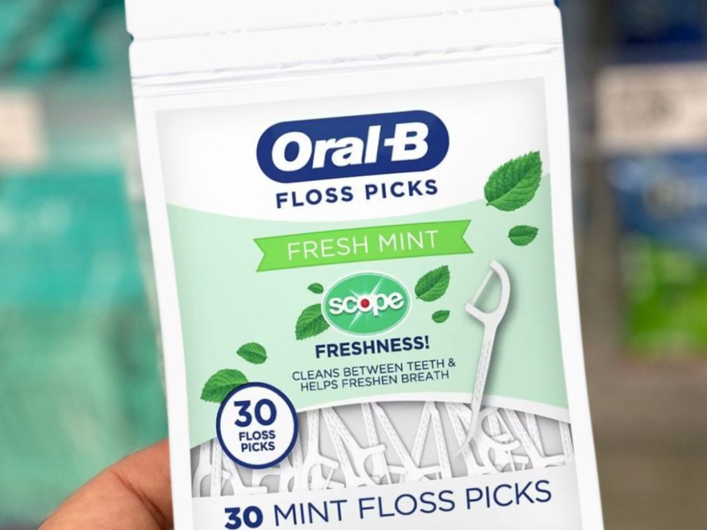 Hand holding a 30-count bag of Oral B Floss Picks