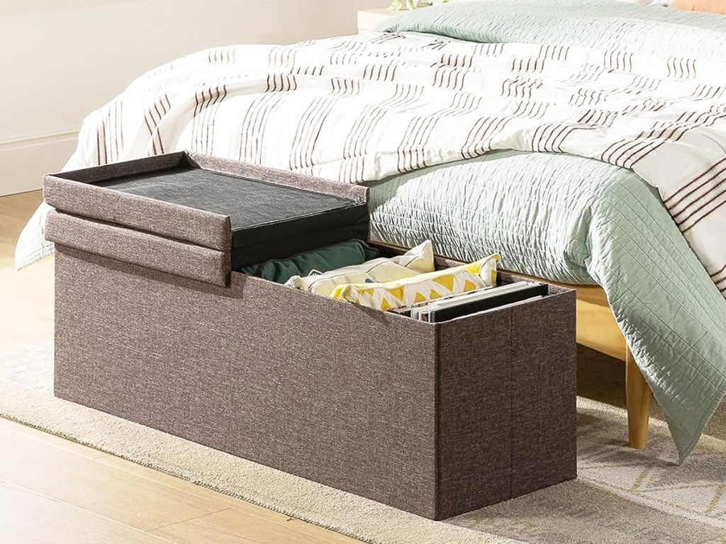 opened storage ottoman at foot of a bed