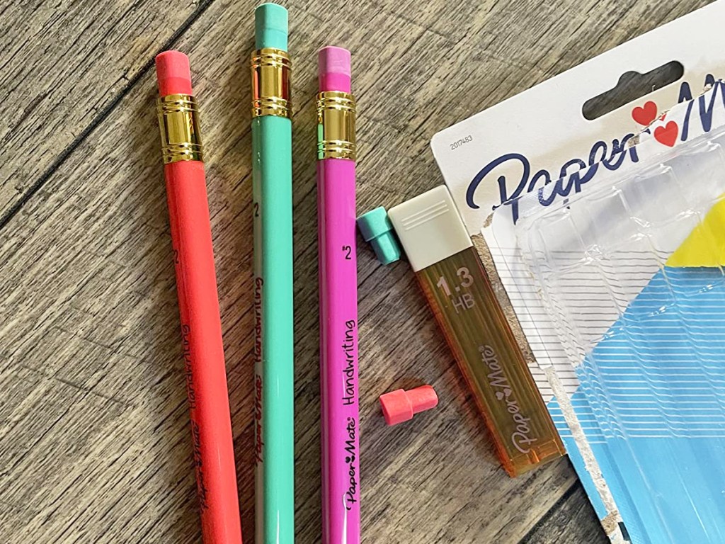 paper mate triangular pencils, lead refill, and two spare erasers on wood table