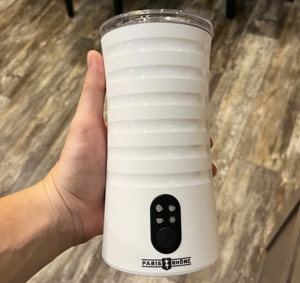 hand holding a white milk frother