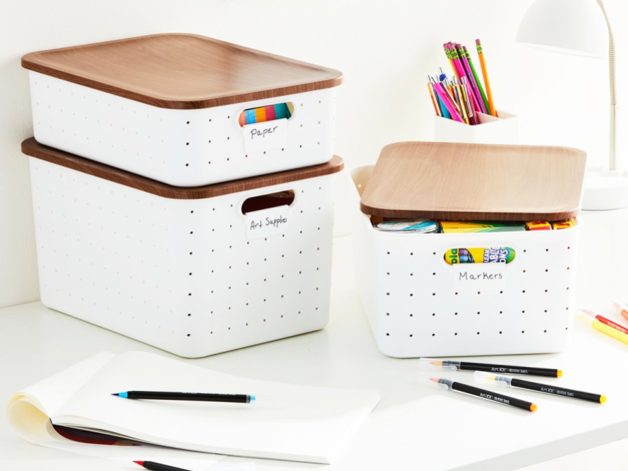 white storage boxes with wood lids on a desk with markers