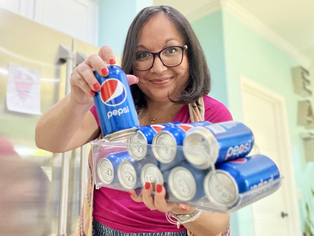woman holding plastic fridge organizer filled with cans of pepsi