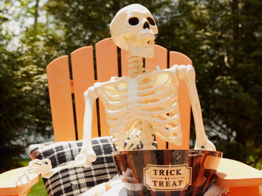 Place & Time 5ft Halloween Posable Skeleton in chair holding trick or treat bowl