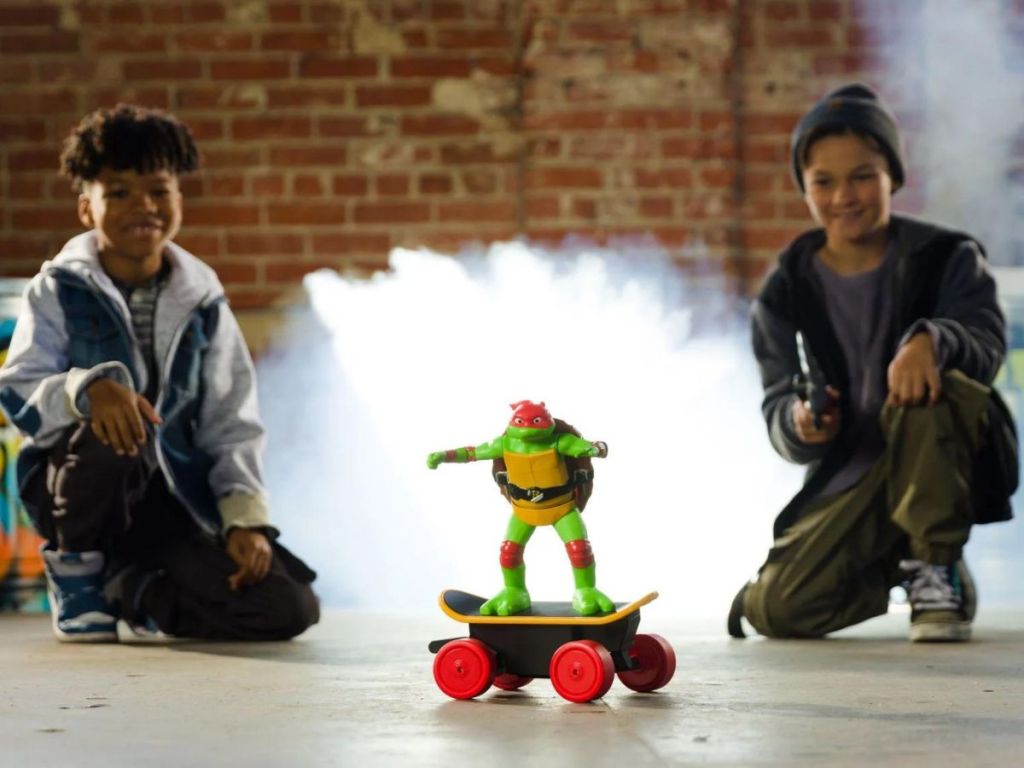 2 kids playing with a TMNT Raphael RC Skateboard toy