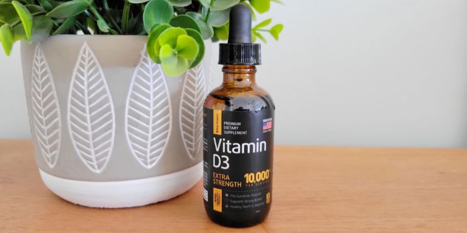 bottle of Vitamin D3 on table with plant beside it