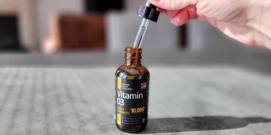 person taking dropper from Vitamin D3 bottle