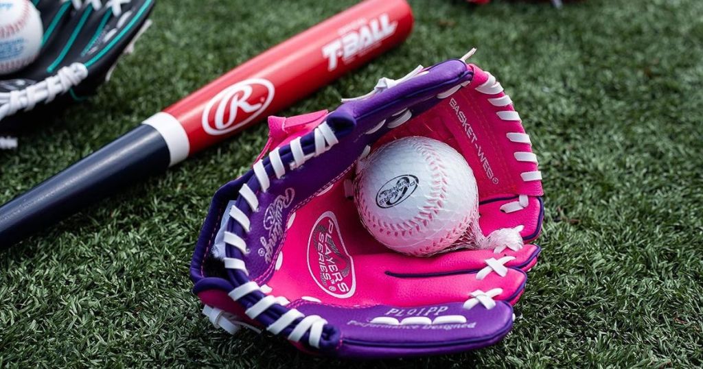 Rawlings Baseball Glove with ball in it laying on the grass next to a bat