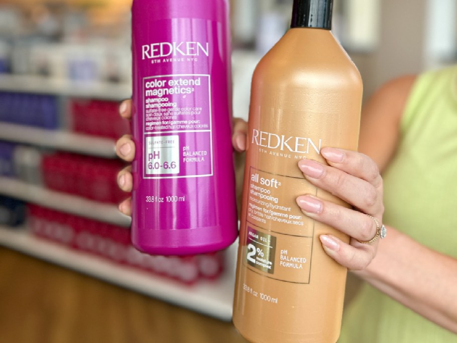 woman holding large bottles of redken hair care