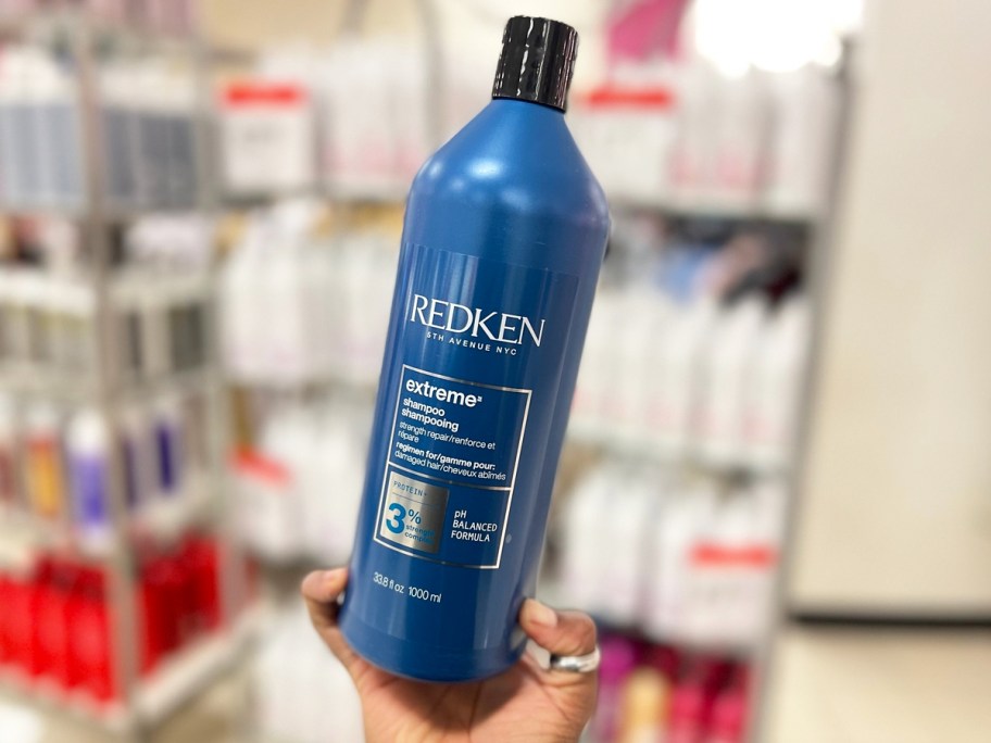 hand holding a blue liter bottle of redken shampoo