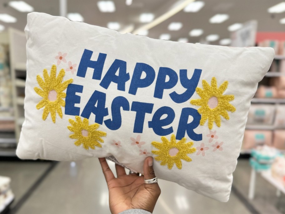 hand holding up a throw pillow that says happy easter with yellow flowers