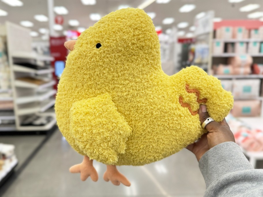 hand holding up a yellow chick throw pillow