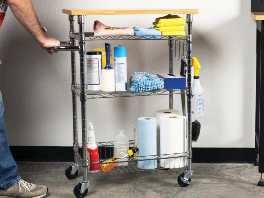 person pushing a metal cart filled with cleaning products