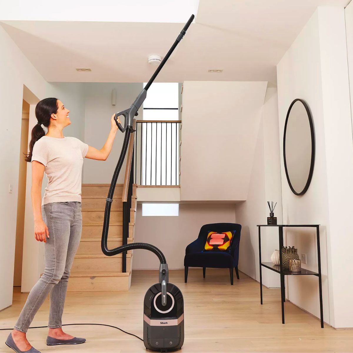 Woman vacuuming ceiling beams with a Shark Bagless Corded Canister Vacuum