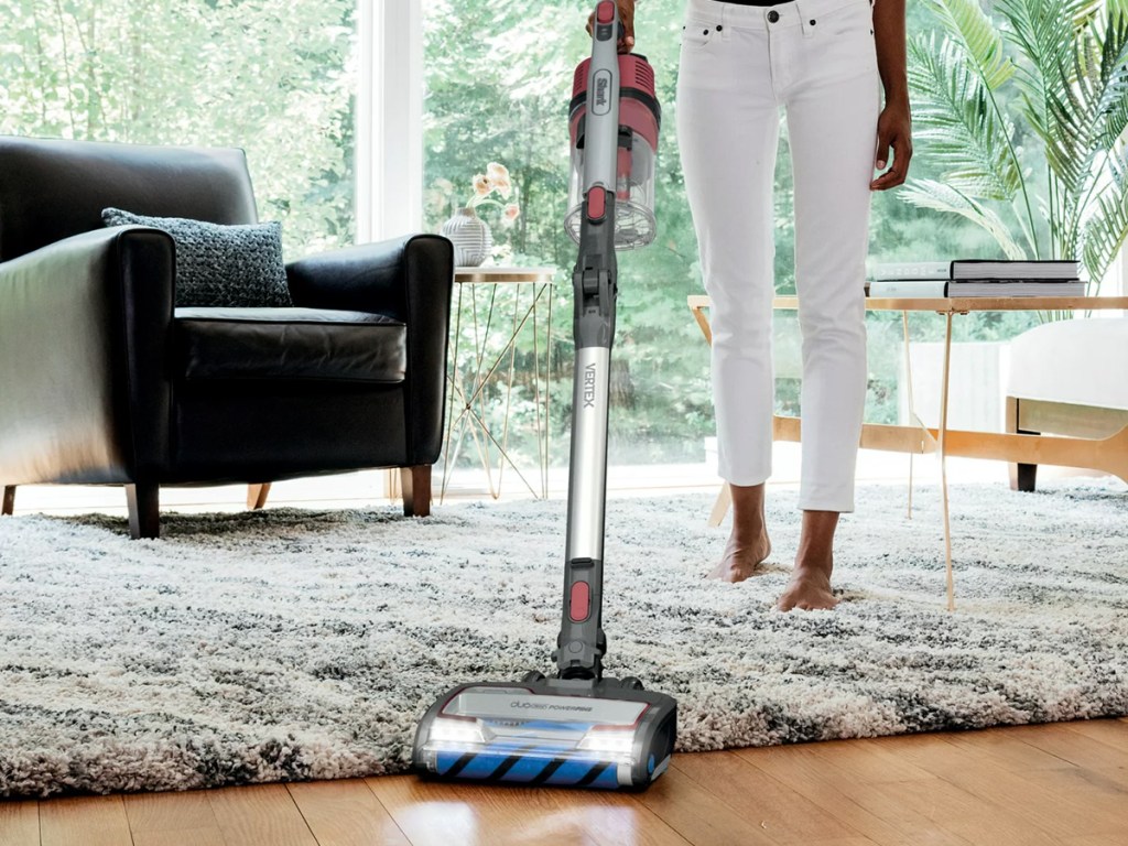 woman cleaning thick rug and wood floors with Shark Vertex Cordless Stick Vacuum