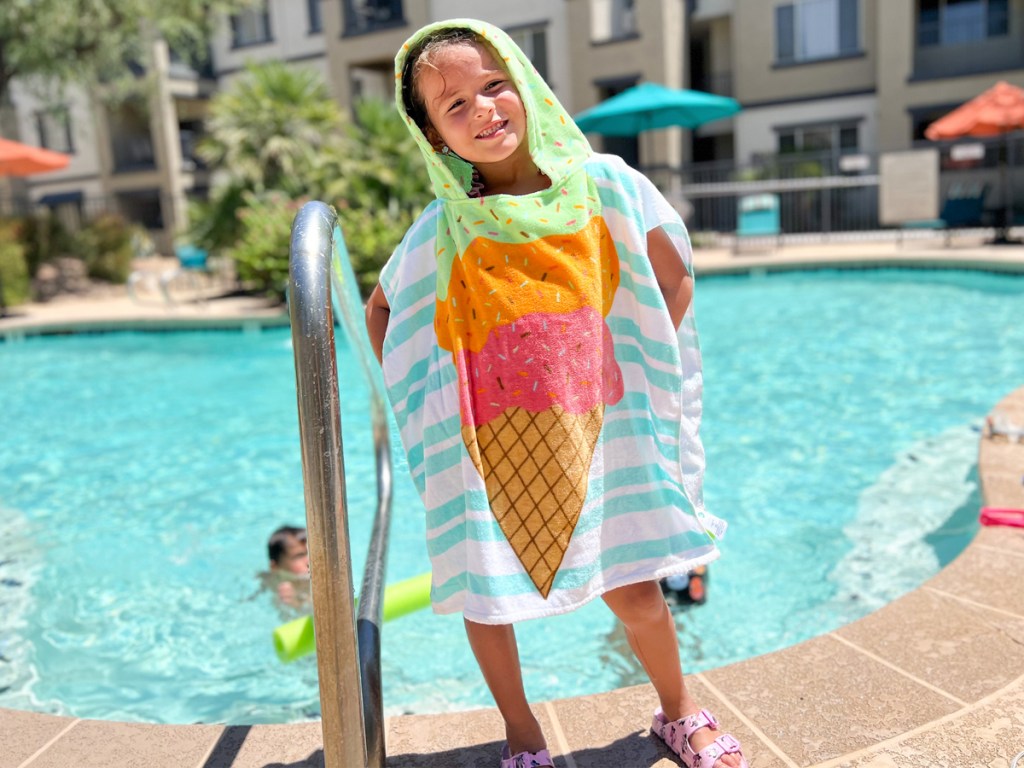 girl standing on side of pool wearing an ice cream print hooded towel