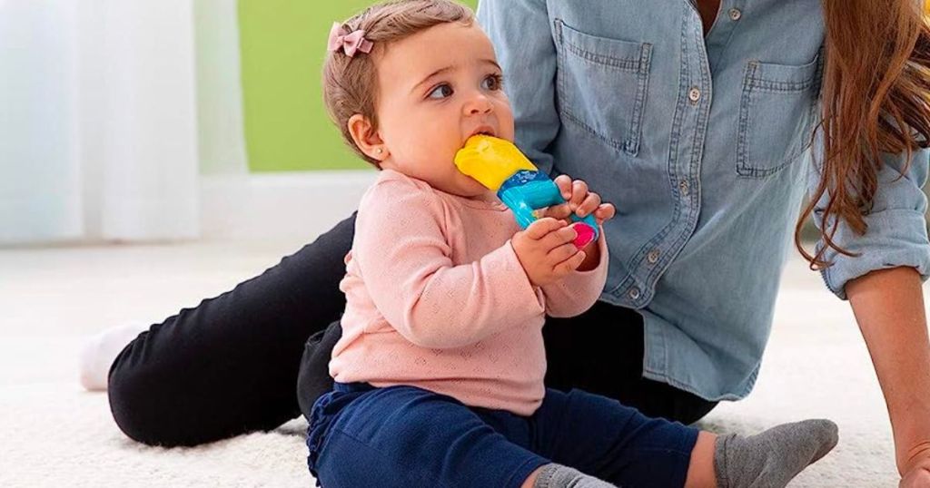 Mom with a baby chewing on The First Years Massaging Action Teether